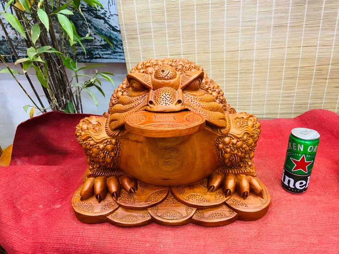 thiềm thừ ngậm tiền gỗ đặt trên nền gỗ phong thủy